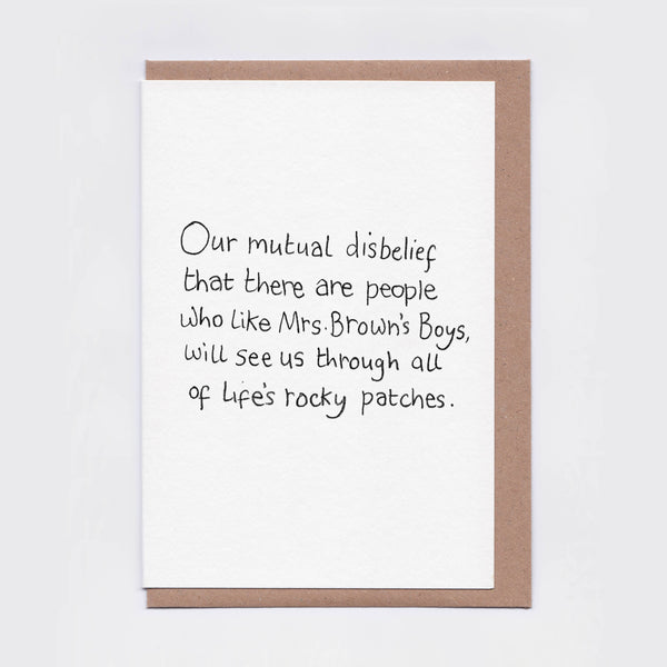 A white greeting card with a brown envelope, featuring the handwritten quote: 'Our mutual disbelief that there are people Who like Mrs. Brown's Boys, will see us through all of life's rocky patches.