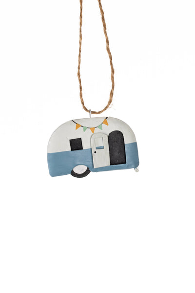 A hand-painted metal Christmas ornament shaped like a retro semi-trailer caravan, featuring a white top half, a light blue bottom half, and colourful bunting, hanging from a natural jute twine string against a plain white background.