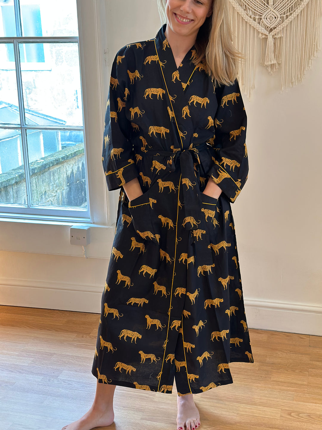 A person standing in a room wearing a black kimono with a jaguar pattern.