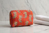 Orange fabric with leopard print held by a hand on a white surface
